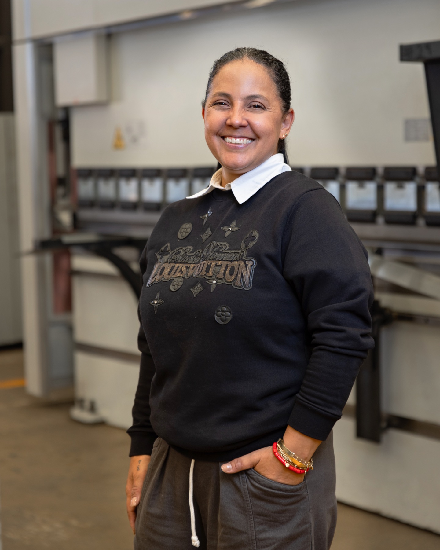 Colaboradora de pie frente a la plegadora CNC, vertical.