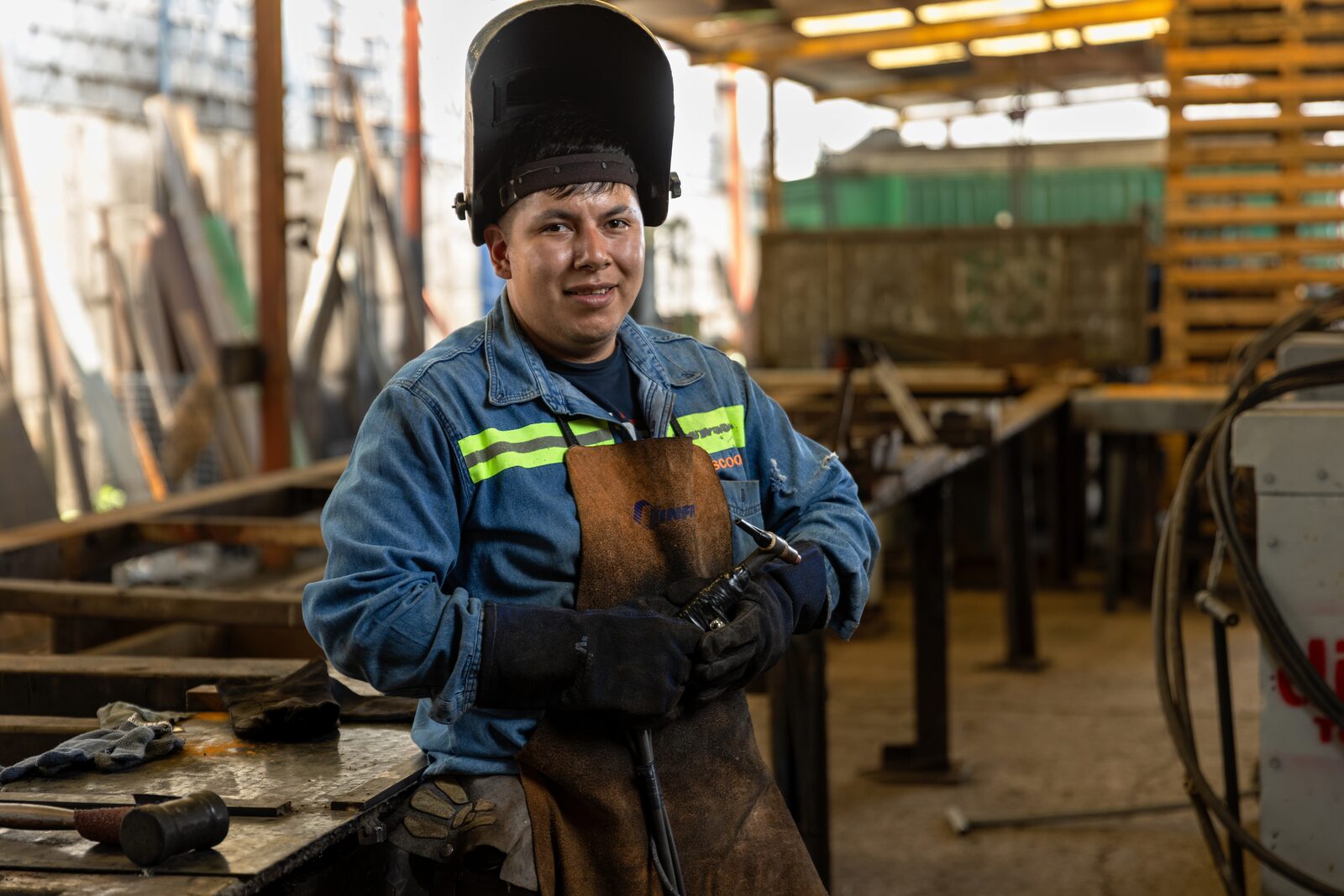 Soldador del taller de estructuras DISCOOM con careta y mandil de carnaza