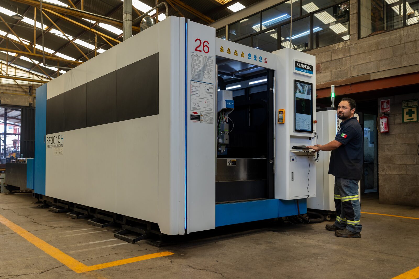Operador en la consola del láser SENFENG SF3015H, máquina completa en cuadro.
