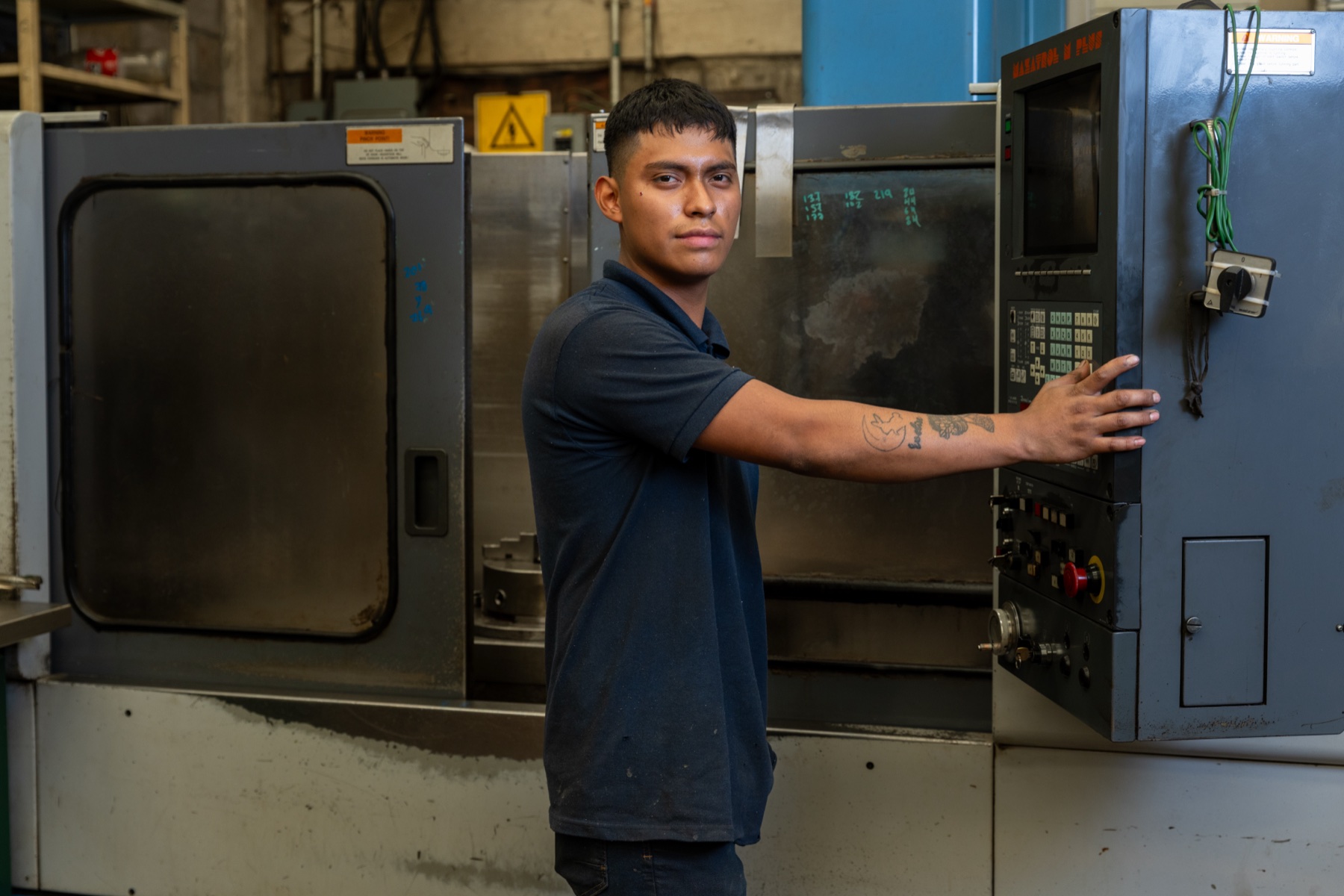 Mismo operador joven, brazo extendido al panel de control encendido.