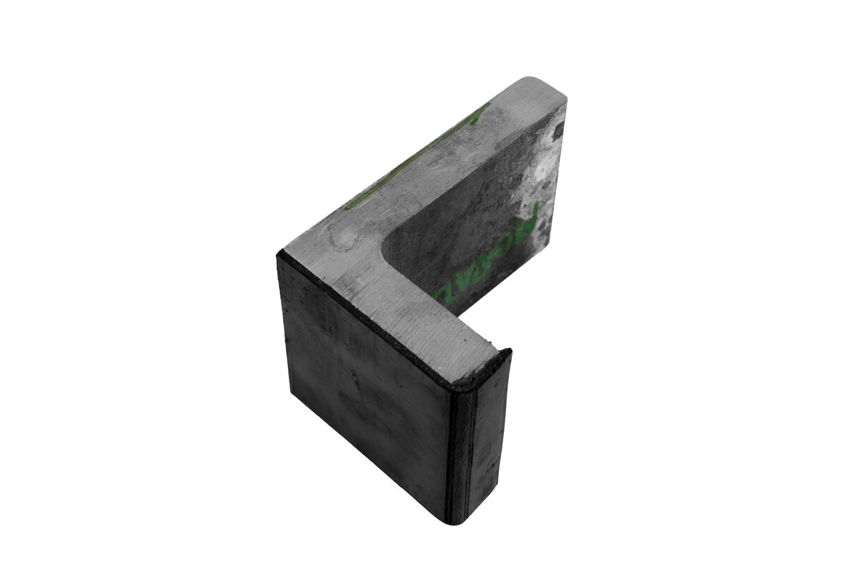 Bloque grueso de acero cortado en C, canto de corte limpio, con restos de película protectora verde.
